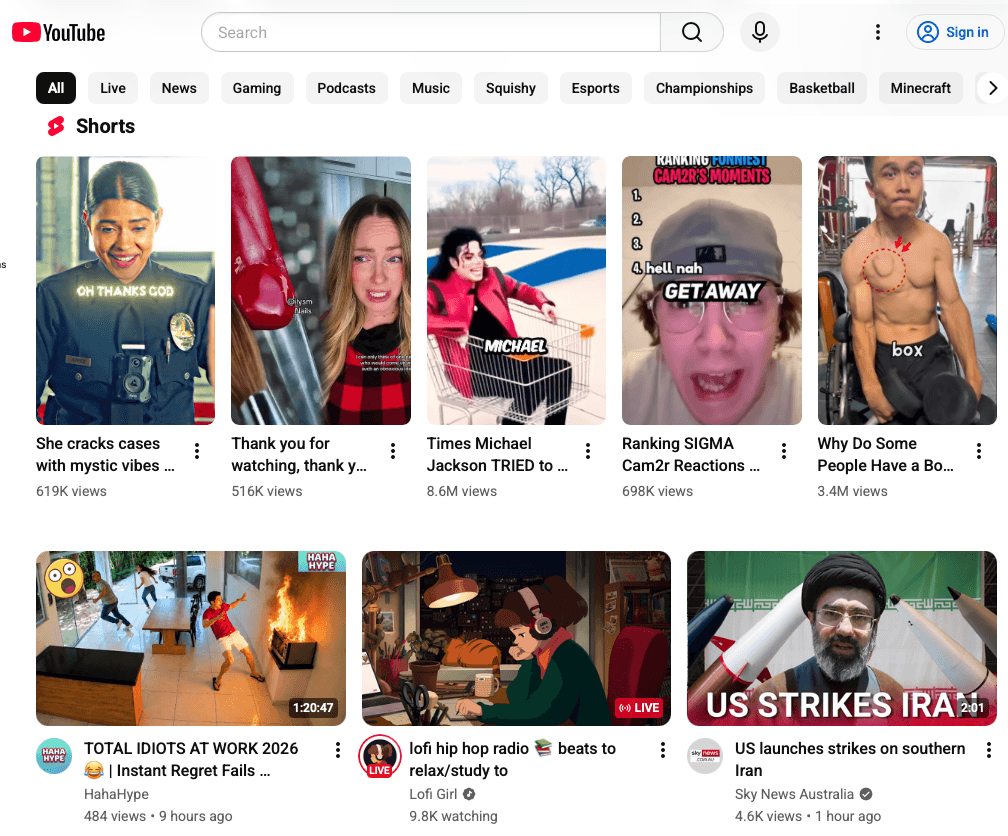 YouTube web home page showing a Shorts row of vertical video thumbnails above a grid of mixed-genre video tiles — news, gaming, music, podcasts — each with engagement counts.